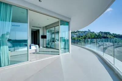 a view from the balcony of a house with glass walls at Veloche Apartment by Continent in Karon Beach