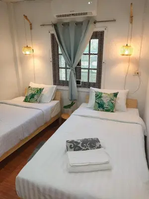 two beds in a room with two windows at Nui's Guesthouse in Ko Yao Noi