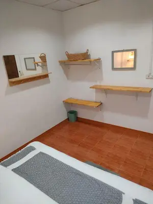 a room with white walls and wooden shelves and a wooden floor at Nui's Guesthouse in Ko Yao Noi