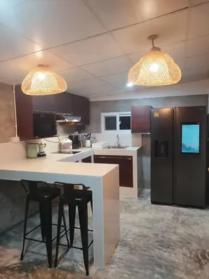 a kitchen with a white counter and a black refrigerator at Nui's Guesthouse in Ko Yao Noi