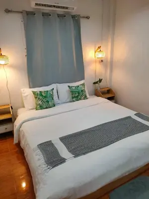 a bedroom with a large white bed with two lamps at Nui's Guesthouse in Ko Yao Noi