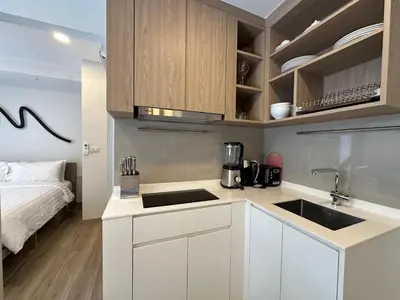 a kitchen with white cabinets and a sink and a bed at 2 BD Skypark Condo with Terrace in Laguna Phuket