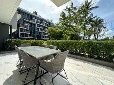 a table and chairs on a patio with a building at 2 BD Skypark Condo with Terrace in Laguna Phuket