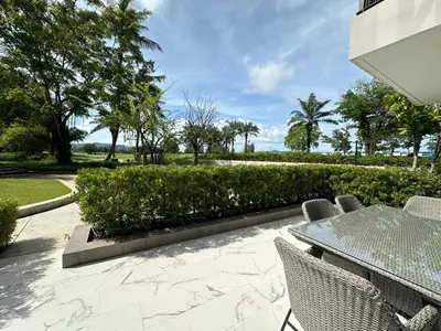 a patio with a table and chairs and bushes at 2 BD Skypark Condo with Terrace in Laguna Phuket