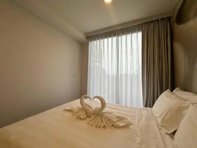 two swans sitting on top of a bed with a window at 1 BD Laguna Skypark Golf Course View in Phuket