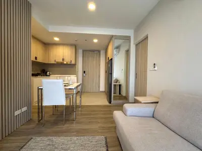 a living room with a couch and a table and a kitchen at 2 BD Skypark Condo in Laguna Phuket