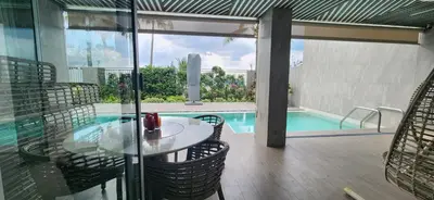 a patio with a glass table and chairs next to a swimming pool at Angsana Beachfront Residences in Phuket