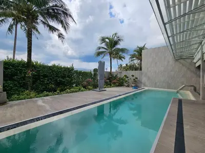 a swimming pool next to a building with palm trees at Angsana Beachfront Residences in Phuket