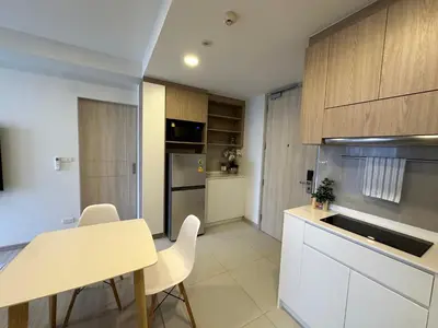 a kitchen with white cabinets and a table and chairs at 2 BD Laguna Skypark Condo in Phuket