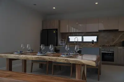 a kitchen with a wooden table with wine glasses on it at Zenithy Villas 3BD in Phuket