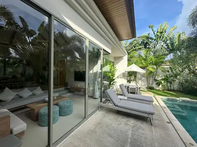 a living room with glass walls and a swimming pool at Trichada Sky 3BD in Phuket