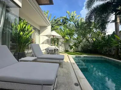a swimming pool with two lounge chairs and an umbrella at Trichada Sky 3BD in Phuket
