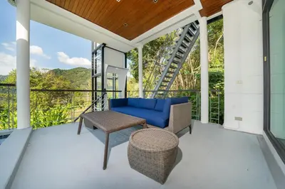 a screened in porch with a blue couch and a table at Amor Primero - sea view pool villa with maid in Kamala Beach