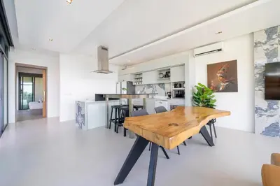 a kitchen and dining room with a wooden table and chairs at Amor Primero - sea view pool villa with maid in Kamala Beach