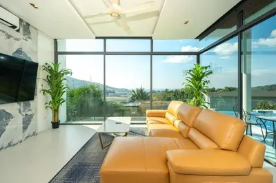 a living room with a couch and large windows at Amor Primero - sea view pool villa with maid in Kamala Beach