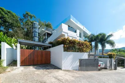 a white house with a gate and a fence at Amor Primero - sea view pool villa with maid in Kamala Beach