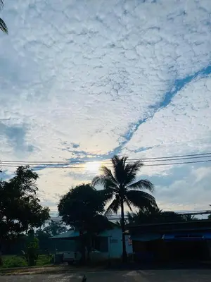 a cloudy sky with a palm tree and a building at Coral Retreat Koh Yao Yai in Ko Thanan