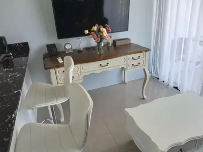 a white desk with a vase of flowers on it at Palmyrah Surin Beach Residence in Surin Beach
