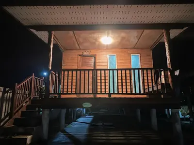 a wooden house with a balcony at night at Friendly house in Ko Phlong