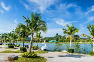 a resort with palm trees and a boat in the water at Chalong Miracle Lakeview in Chalong