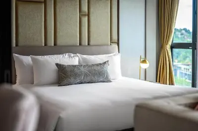 a white bed with a pillow and a window at Private Residents in Surin Mida in Surin Beach
