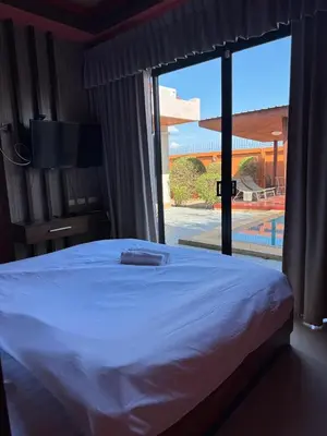 a bedroom with a white bed and a large window at Pool villa Phuket in Kata Beach