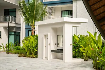 a white building with a palm tree in front of it at Title Halo Romantic Suite Pool View Gym in Nai Yang Beach