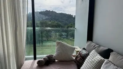 a teddy bear sitting on a couch in front of a window at Patong Sea View pool view condo in Patong Beach