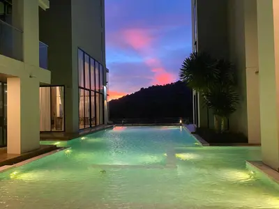 a swimming pool in the middle of a building with a sunset at Patong Sea View pool view condo in Patong Beach