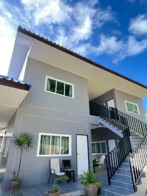 a white house with a staircase and some plants at Boonyawat Apartment in Kata Beach