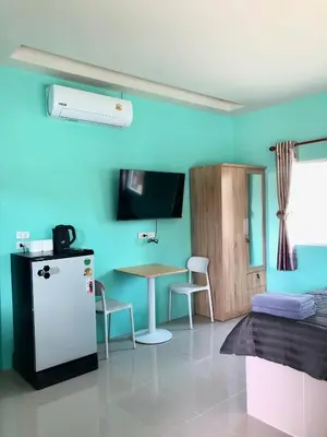 a room with a refrigerator and a table and a bed at Boonyawat Apartment in Kata Beach