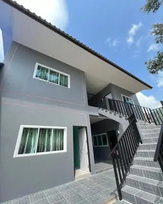 a white house with stairs in front of it at Boonyawat Apartment in Kata Beach