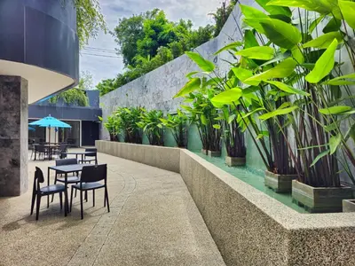 a patio with tables and chairs and potted plants at La Vita 5 Stars Great 1 Bdr 3 Pool in Phuket Town