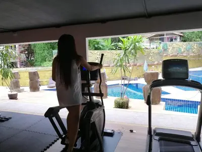 a woman standing on a treadmill in a gym at Ocean and Mountainviews, 2 Balconies in Patong Beach