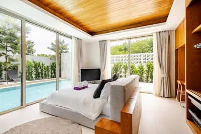 a bedroom with a bed and large windows and a pool at Lux Pride Villa 3 bedroom Phuket Bang-Tao beach in Ban Phak Chit