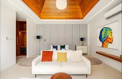 a bedroom with a white bed with colorful pillows at Lux Pride Villa 3 bedroom Phuket Bang-Tao beach in Ban Phak Chit