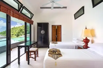a bedroom with two beds and a desk and windows at 10 - Panoramic View on Ao Yon Beach in Ko Thanan