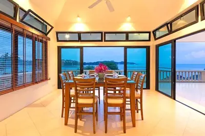 a dining room with a table and chairs and the ocean at 10 - Panoramic View on Ao Yon Beach in Ko Thanan