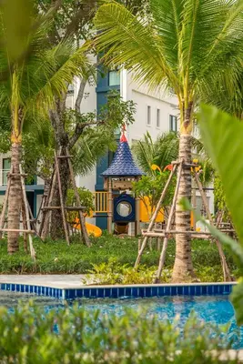 a playground with a clock and palm trees in front of a building at Title Halo I love Asia Naiyang Pool Gym in Nai Yang Beach