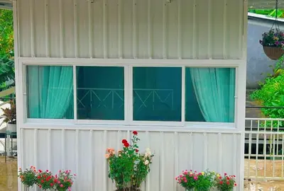 a white building with two windows and flowers at Camping Phuket 88 in Kathu