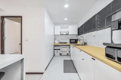 a kitchen with white cabinets and a wooden counter top at Sawansa 20 3BR 300m2 Modern Seaview house near Beach in Patong Beach