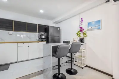 a kitchen with white cabinets and a counter with two chairs at Sawansa 20 3BR 300m2 Modern Seaview house near Beach in Patong Beach