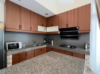 a kitchen with wooden cabinets and a microwave at Ocean Villa Bang Tao Phuket in Ban Thalat Choeng Thale