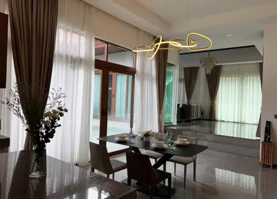 a dining room with a table and chairs and a chandelier at Ocean Villa Bang Tao Phuket in Ban Thalat Choeng Thale