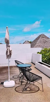 a patio with a chair and a table and a umbrella at Skyframe pool villa near Bangtao beach, Bluetree, Thalang in Ban Pak Lak