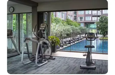 a room with a gym with a view of a pool at Dcondo kuku resort in Ban Phlu Yai