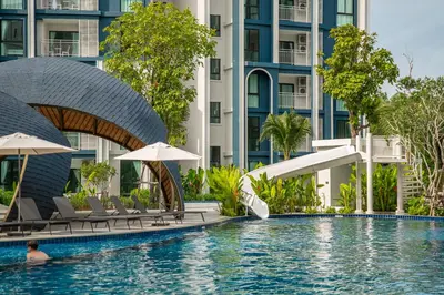 a person swimming in a pool in front of a building at Title Halo Holi Day 40m2 King Bed Pool View in Nai Yang Beach