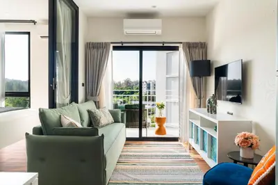 a living room with a couch and a tv at Title Halo Holi Day 40m2 King Bed Pool View in Nai Yang Beach