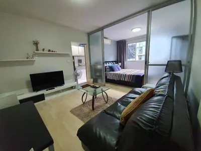 a living room with a black leather couch and a television at Dcondo Kathu Poolview by LaChambre Phuket in Phuket Town