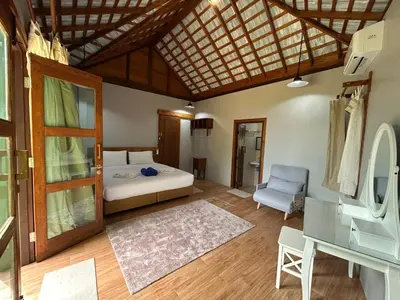 a bedroom with a bed and a chair in a room at Rawi Seaside Cottage, Ko Yao Noi in Ban Laem Sai